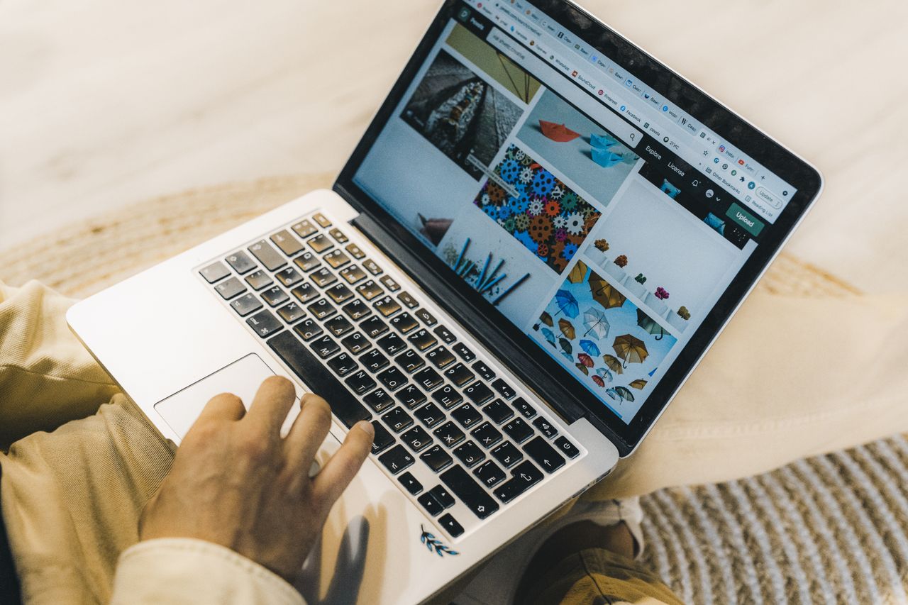 gallery-04 A person using a laptop to browse stock photo websites. Freelancing work in a cozy setting.