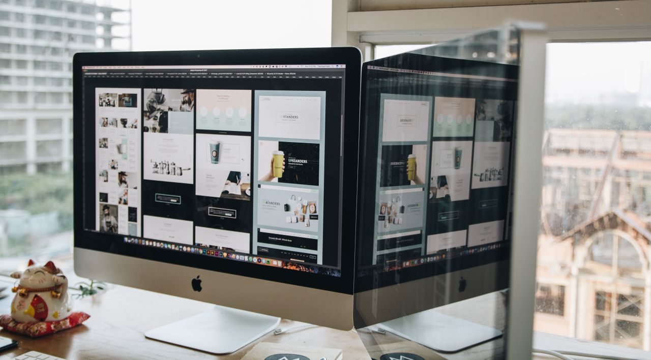 home-img Dual monitors on a desk, showcasing web design in a modern office setting.